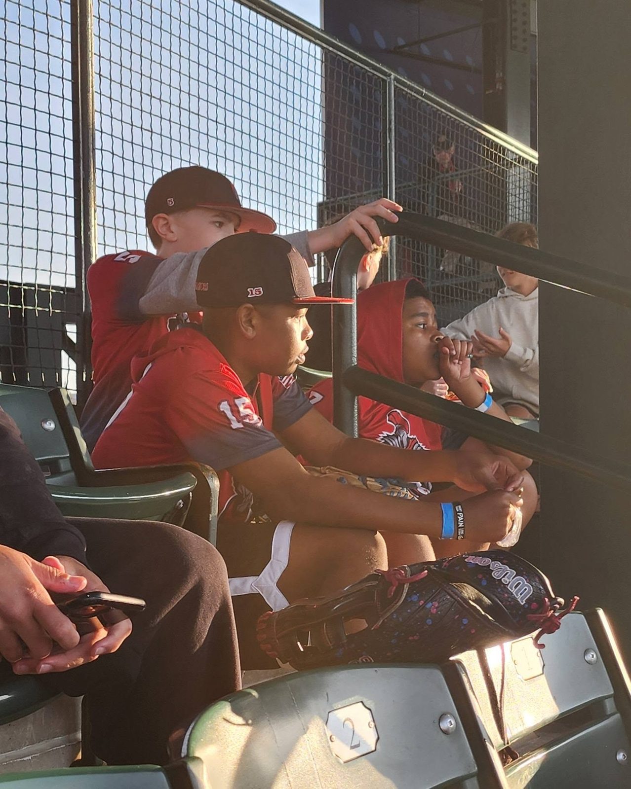 Players watching a game from the stands at sunset